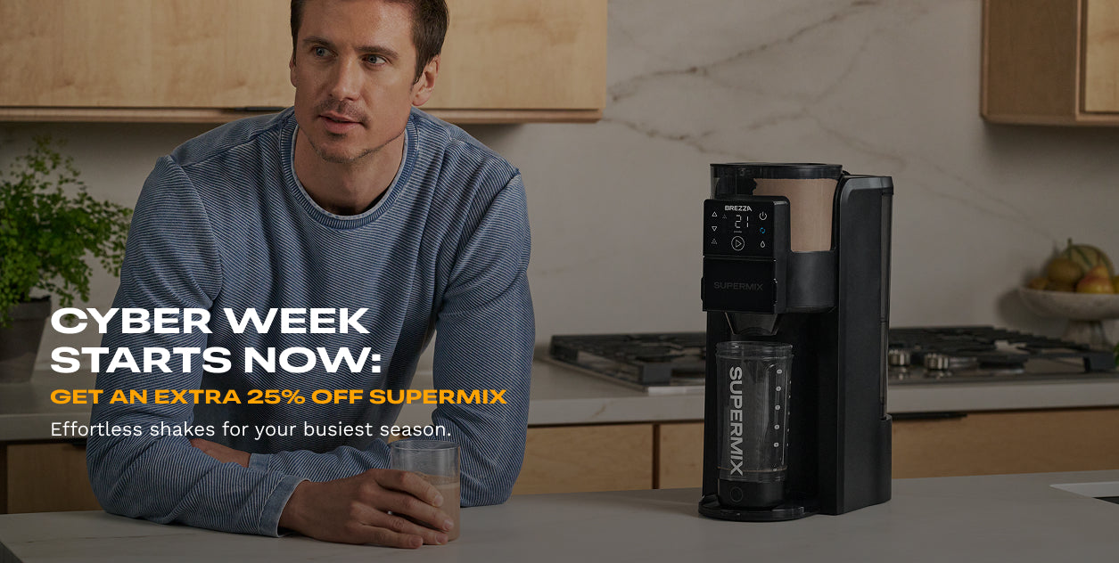 Man sitting at a kitchen counter with a Supermix shake maker and glass of shake, Cyber Week promotion text overlay.